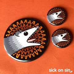 A cute illustration of a possum with its mouth wide open and text of AAAAaaaa in a spiral behind him. An original design by Sick On Sin available on pins, magnets, keychains, etc.