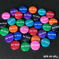 A pile of colourful 1 inch buttons with the slogan Be Kind on them. An original design by Sick On Sin available on pins, magnets, keychains, etc.