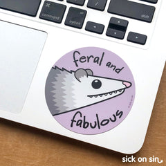 Super cute vinyl sticker featuring an original design of a possum with slogan 'feral and fabulous' by Sick On Sin on a laptop