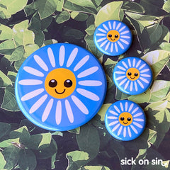 A collection of flair pieces featuring a simple design of a happy daisy flower. A cute original design by Sick On Sin available on pins, magnets, keychains, etc.