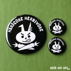 A cute illustration of a sneering punk bunny rabbit with carrot crossbones and the text Hardcore Herbivore. An original design by Sick On Sin available on pins, magnets, keychains, etc.