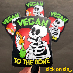 Collection of spooky cute vinyl stickers featuring a happy skeleton holding a carrot, giving thumbs up and the slogan Vegan To The Bone. An original design by Sick On Sin.